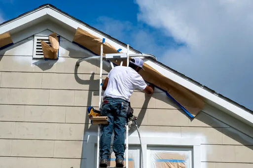 Painter masking windows on a Porter Ranch stucco home before spraying